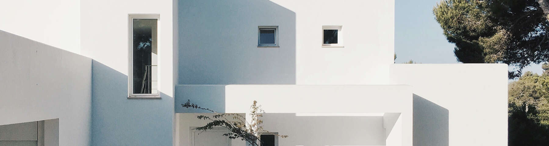 A white building with two windows and one window is open.